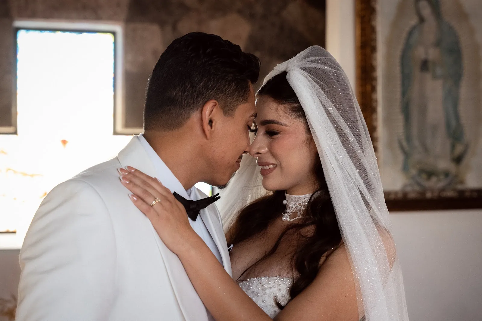 La pareja se besa bajo el velo en el jardín de la hacienda