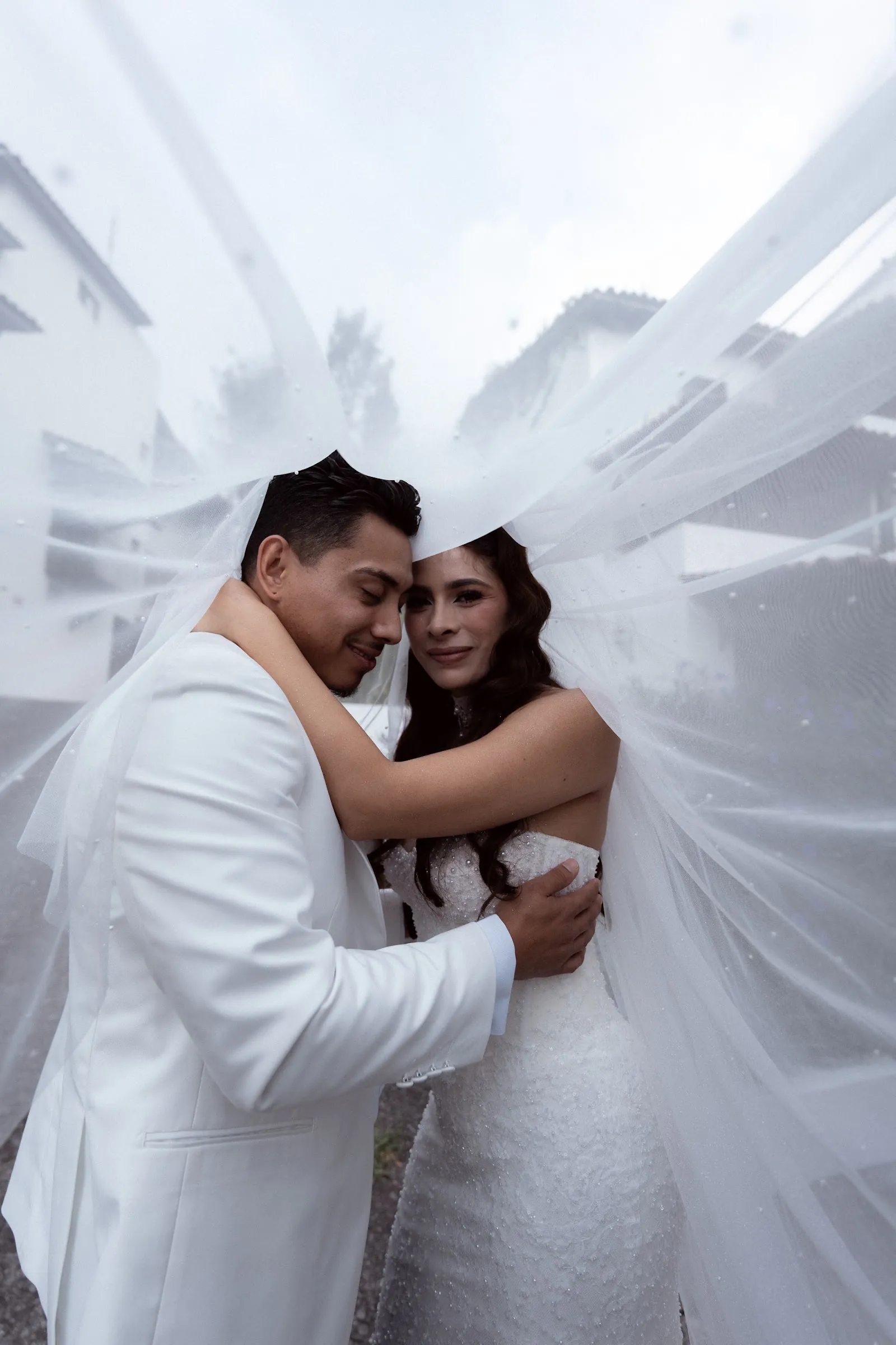 La pareja se besa cubierta por el velo