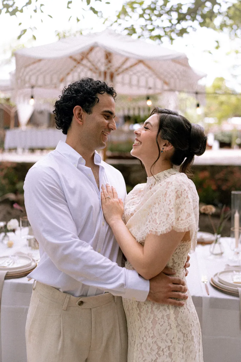 Gus y Karla ríen frente a frente en el patio de su boda en hacienda