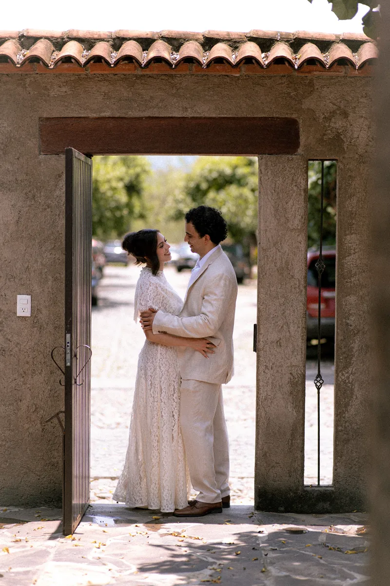 Gus y Karla se abrazan bajo un arco de teja de la hacienda