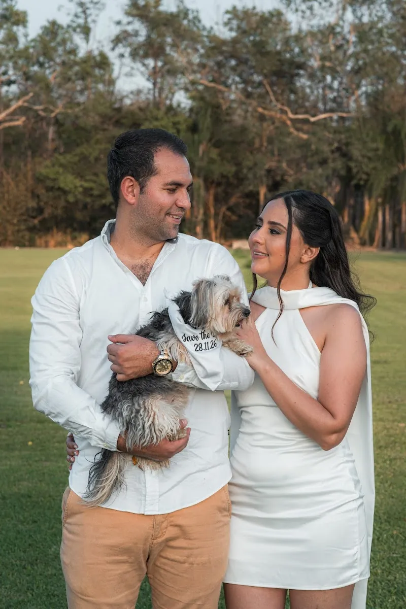 Carlos carga a su perro mientras Paola lo acaricia, los dos sonriendo