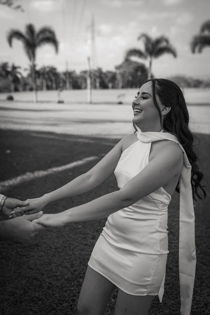 Paola riendo mientras Carlos la toma de las manos en el campo, fotografía en blanco y negro