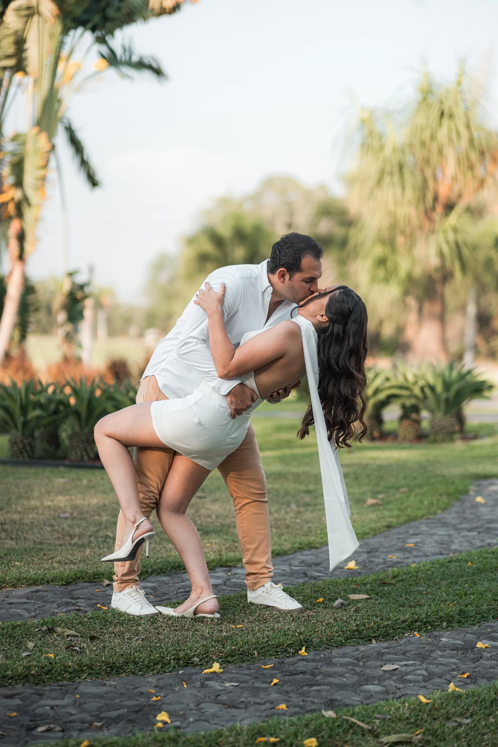 Carlos inclina a Paola en un beso en el jardín